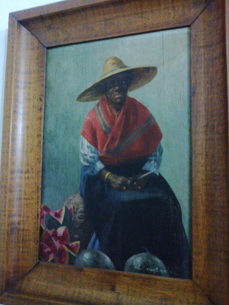 Mulher sentada com chapéu de palha e lençol colorido